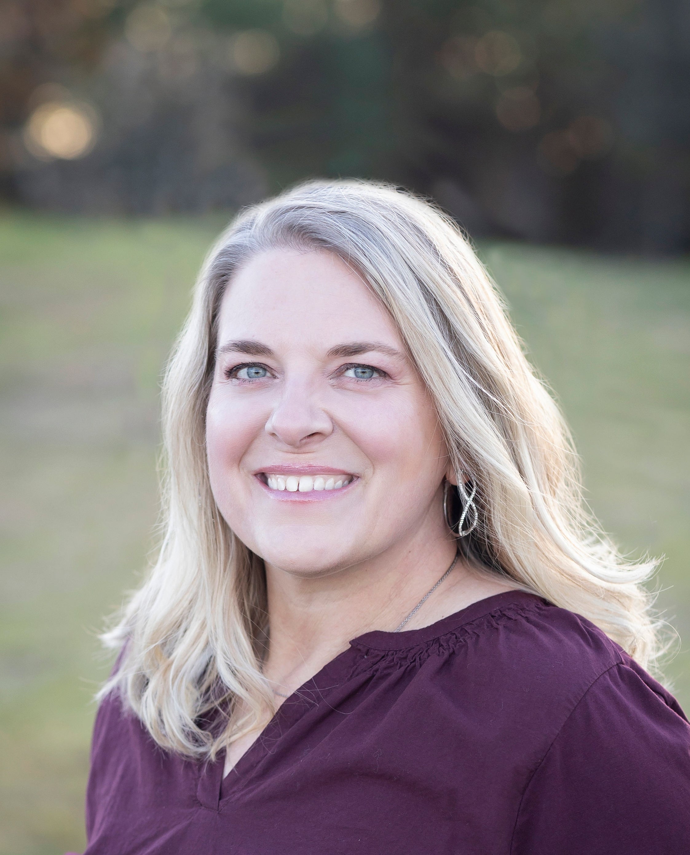 Woman with blonde hair wearing a purple top outdoors